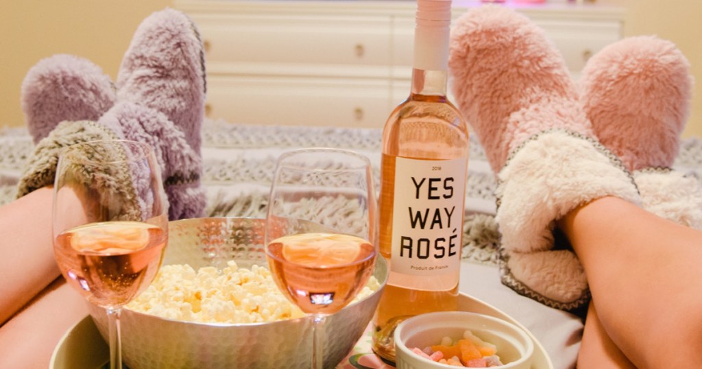 2 women wearing Dearfoams Bootie Slippers and drinking wine