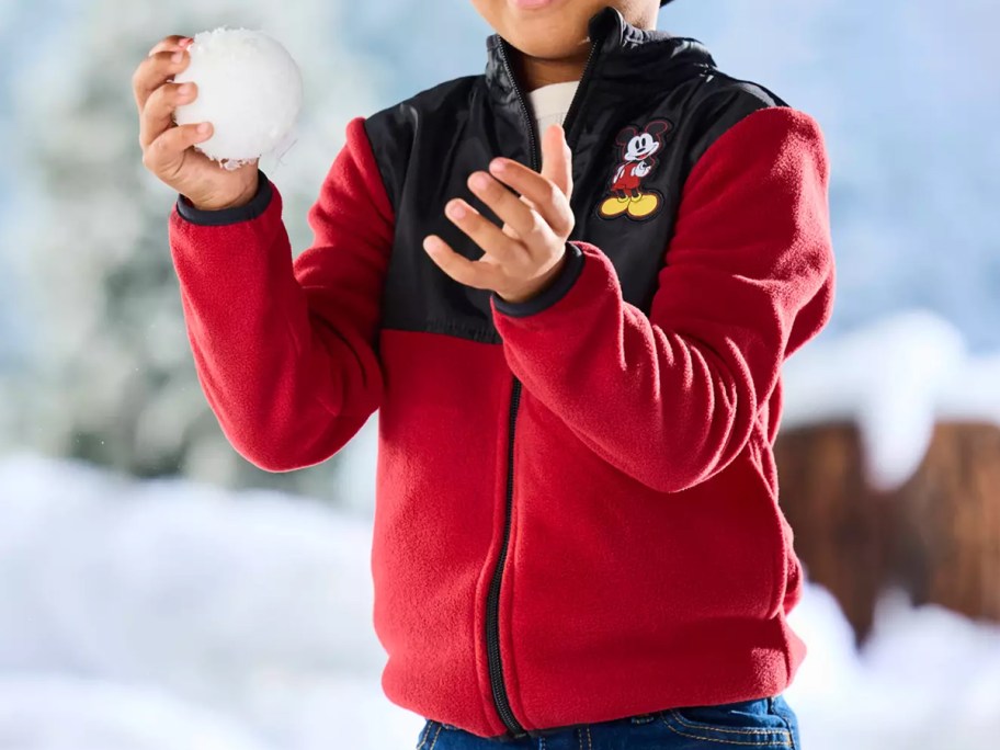 boy in a red and black jacket throwing a snowball