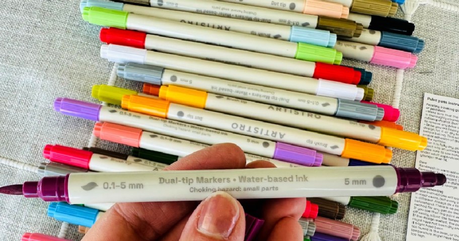 person holding dual tip paint pens