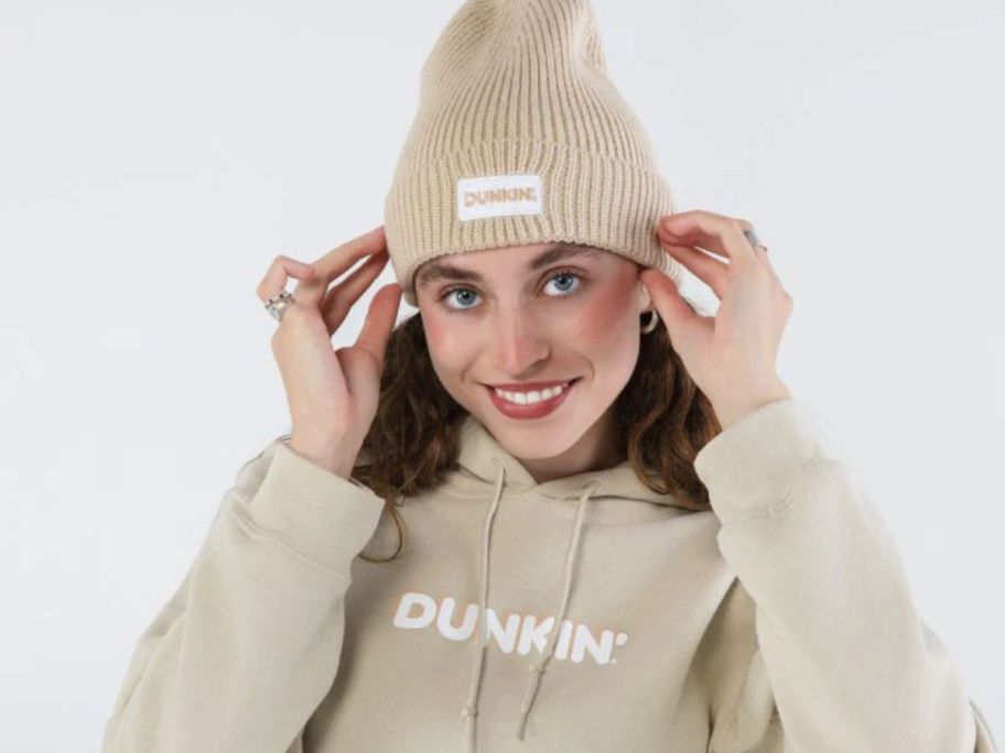 A woman wearing a Dunkin Beanie and Sweatshirt