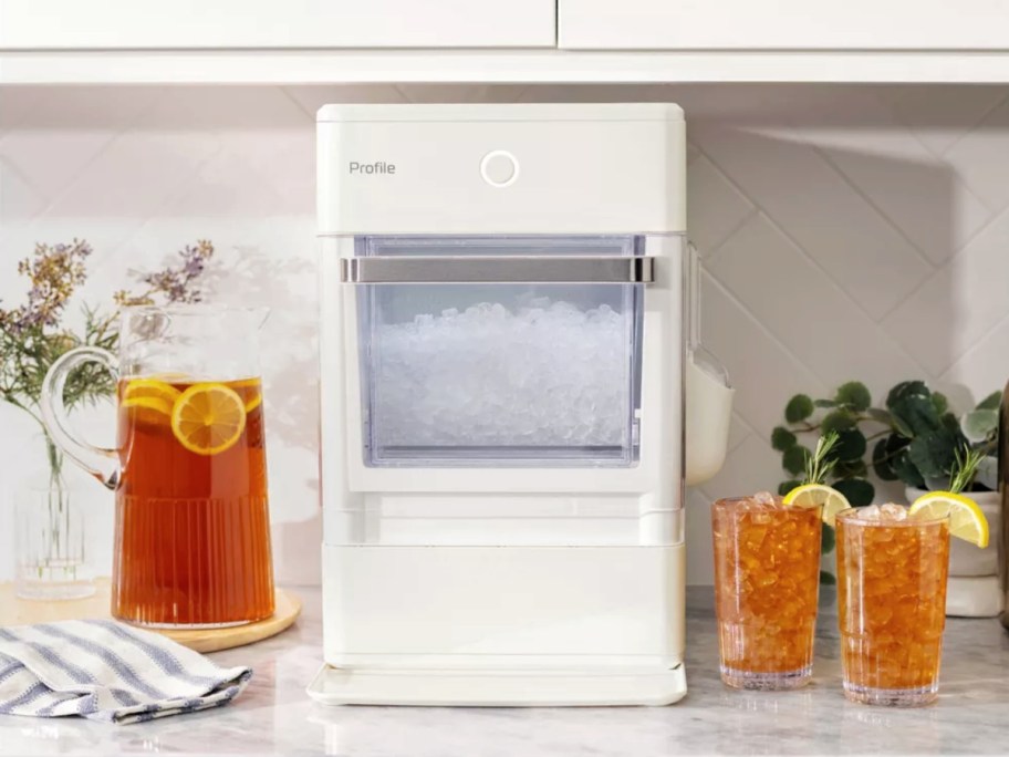 white GE Hearth & Hand Nugget Ice Make, pitcher of iced tea and 2 glassed with ice tea and lemon wedges on a counter