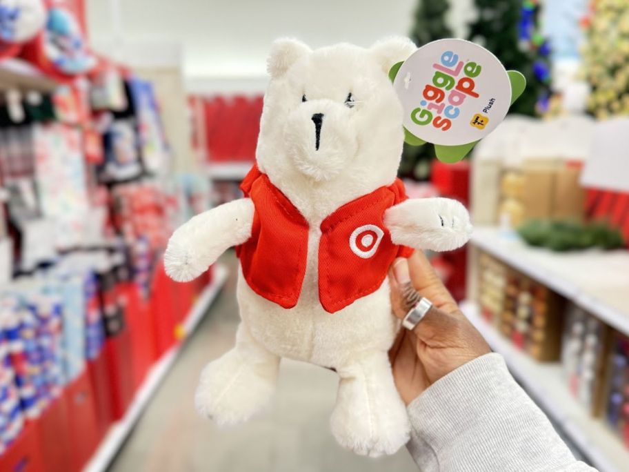 a womans hand holding a gigglescape plush bear in target vest