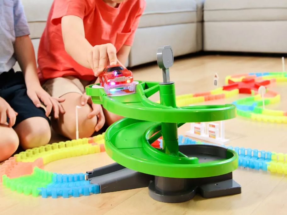 Two little boys playing with a STEM Glow In The Dark Trax 360-piece Race Tracks Set