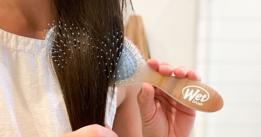 woman with long brown hair using a Wet Brush brand hair brush to brush her hair