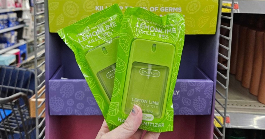 hand holding 2 green color hand sanitizers in the packaging they onlinee in