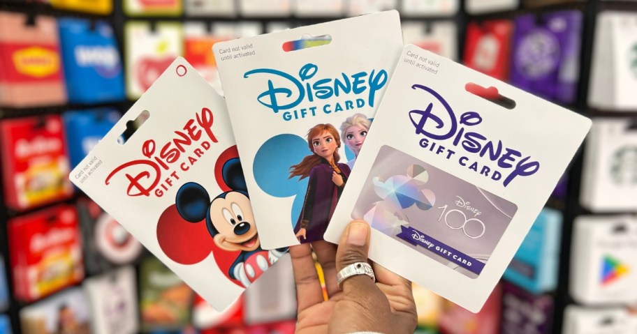 hand holding Disney Gift Cards with Mickey, Anna and Elsa, and a Disney 100 design on them