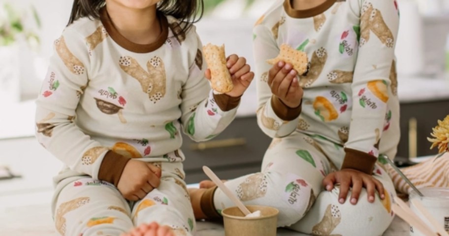 a little girl and boy wearing matching pajamas sitting on the floor