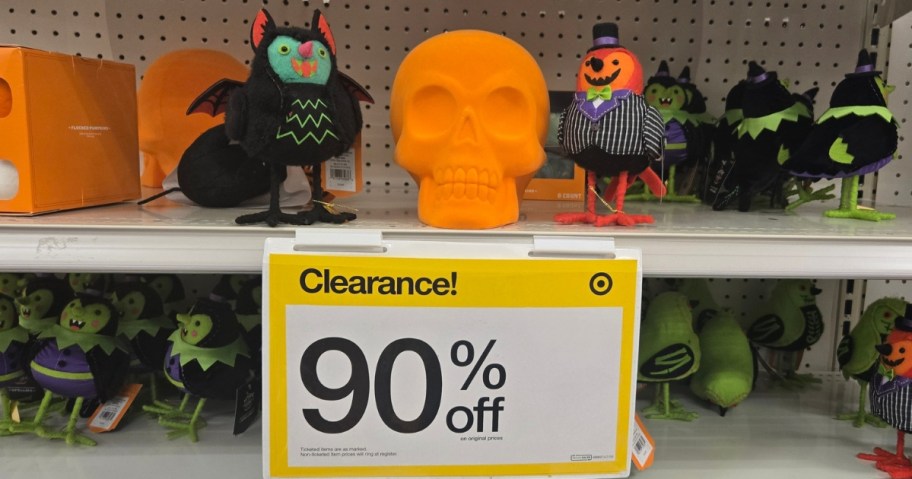 Target store shelves with Halloween decor on them and a yellow and white sign that says "Clearance 90% off"