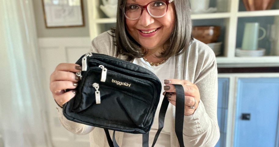 woman holding up a black Baggallini purse to the camera