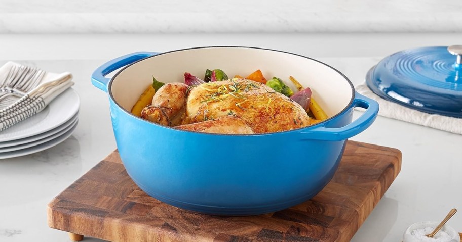 a blue dutch oven pot with food in it, lid beside it, sitting on a kitchen counter