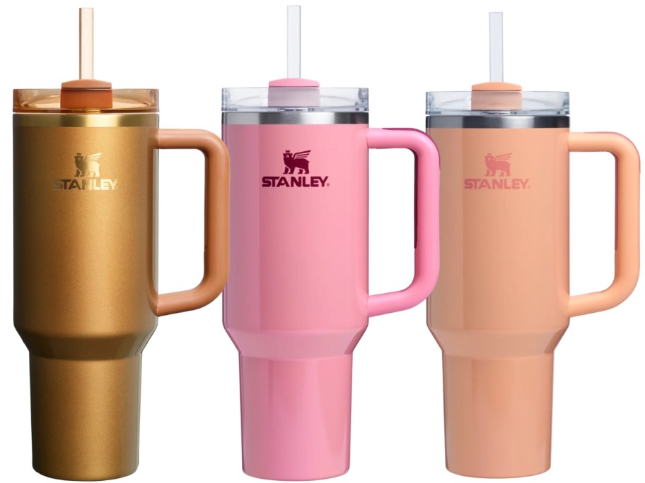 3 Stanley Tumblers, one in a copper shiny color, one in a pink shimmery color and one in a light peach shimmery color