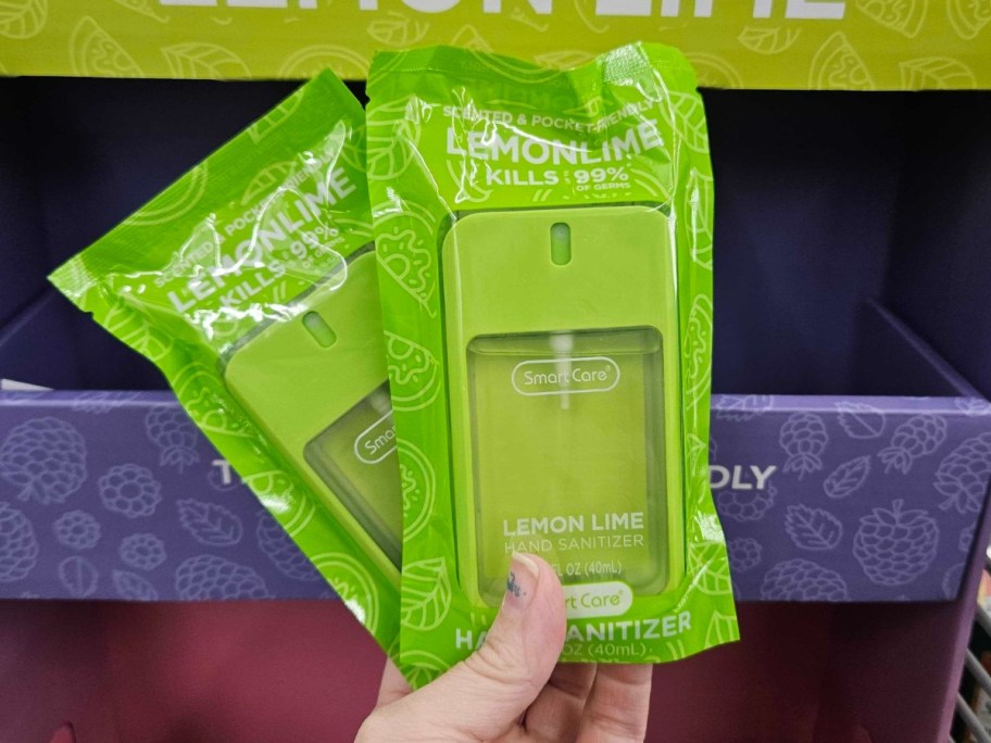 hand holding 2 green color hand sanitizers in the packaging they onlinee in