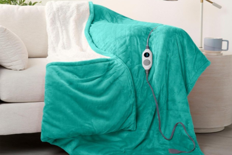 Heated throw blanket draped on the end of a couch, with the electric timer cord overtop.