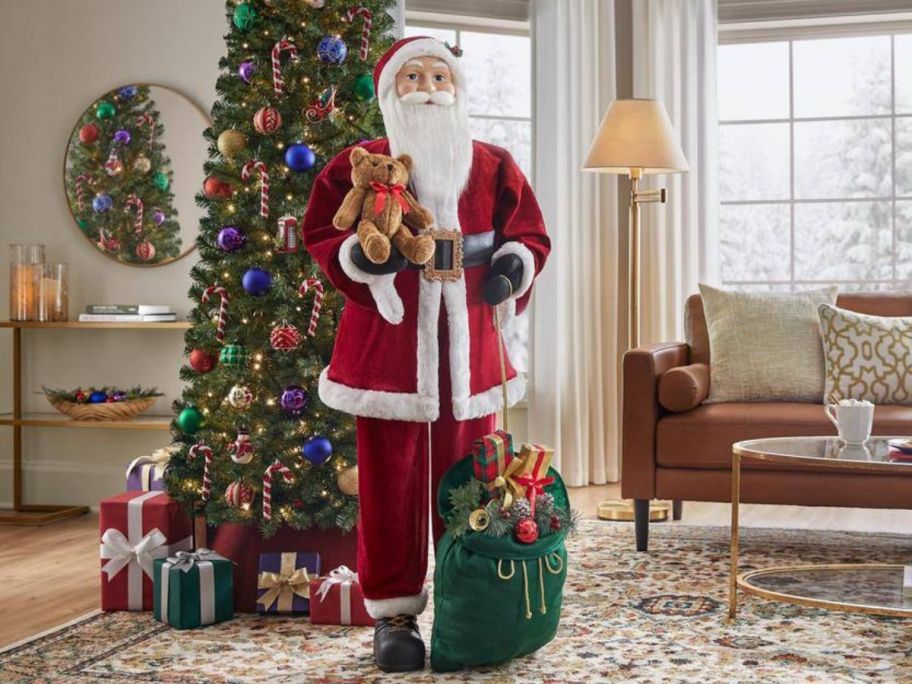 A large Standing Santa in front of a Christmas Tree