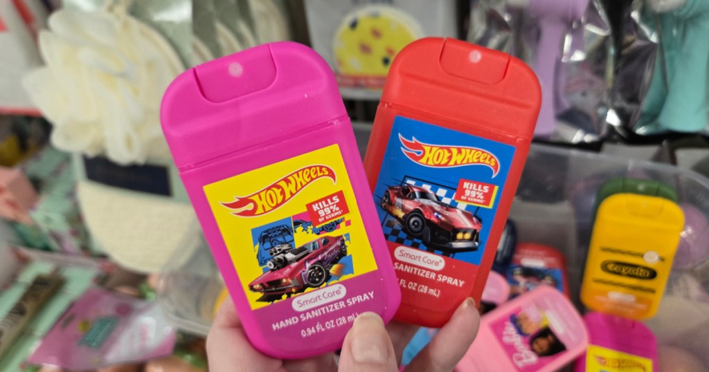 Woman holding up pink and red hot wheels kids hand sanitizer spray sprays inside Dollar tree