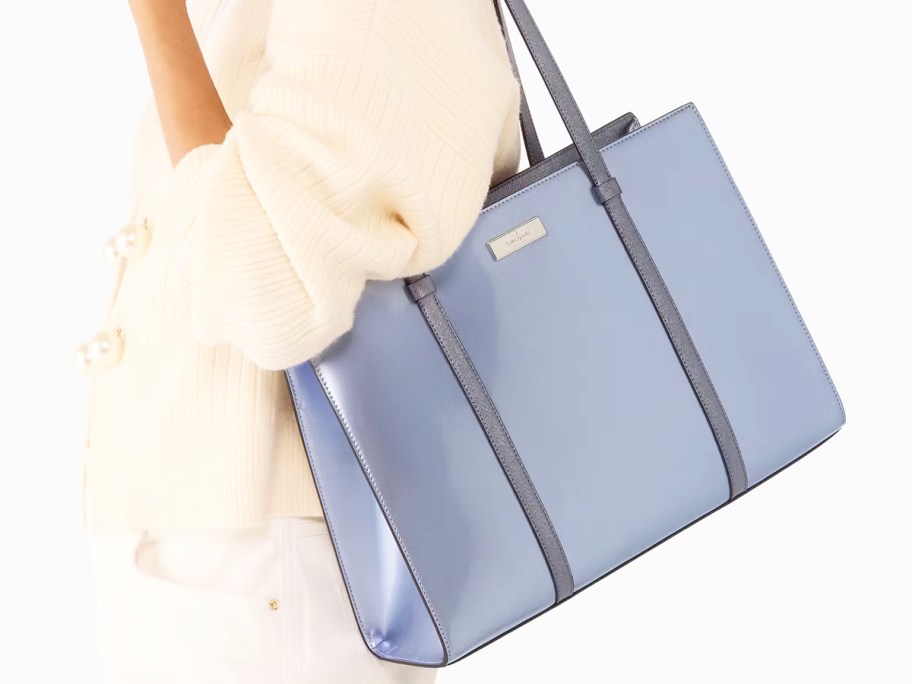 woman in a white sweater with a metallic blue tote bag