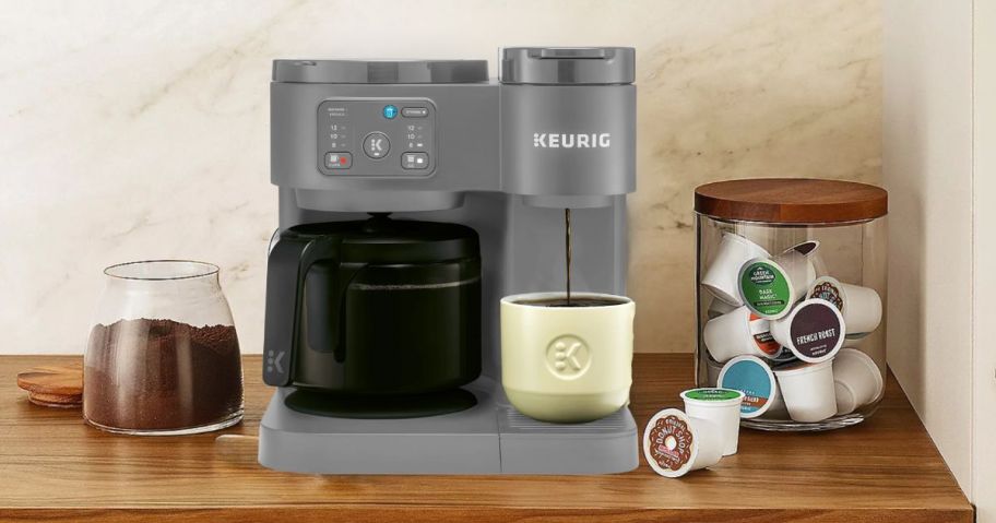 Keurig K-Duo Essentials Coffee Maker & Carafe in Moonlight Grey on counter next to coffee grounds and K-Cups