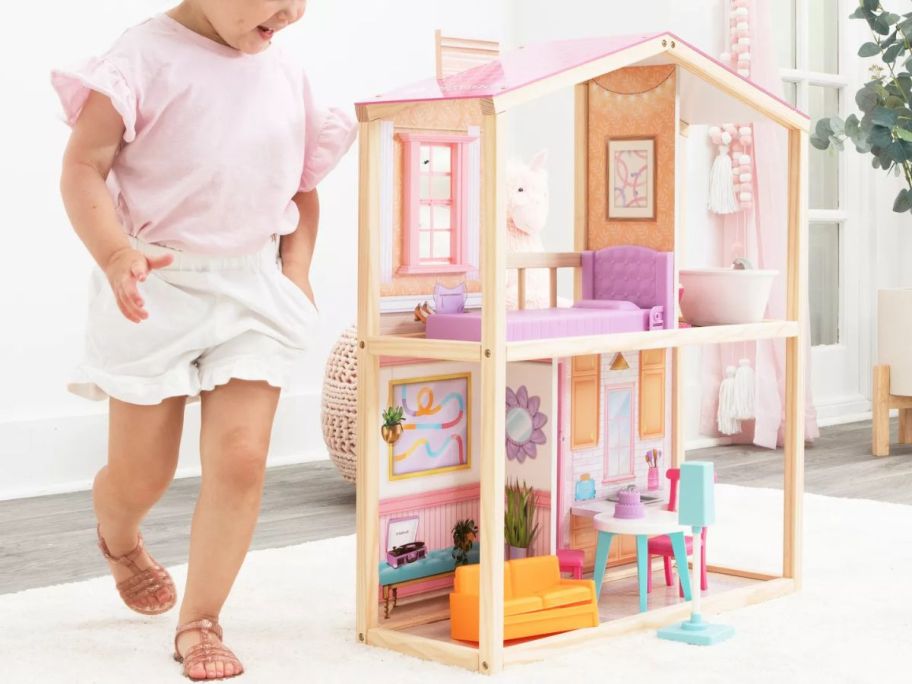 Little girl playing with a Kidkraft dollhouse