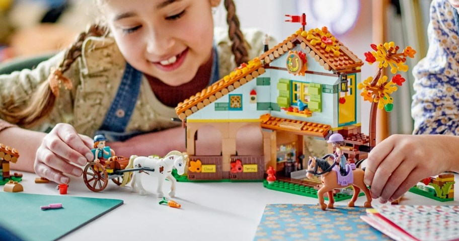 kids playing with a LEGO set with horse's and a stable