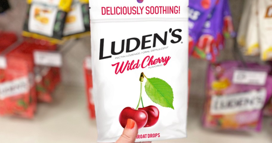 hand holding a white bag of Luden’s Wild Cherry Throat Drops in store