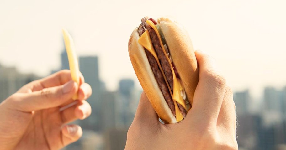 hands holding a McDonald's Double Cheeseburger and a fry