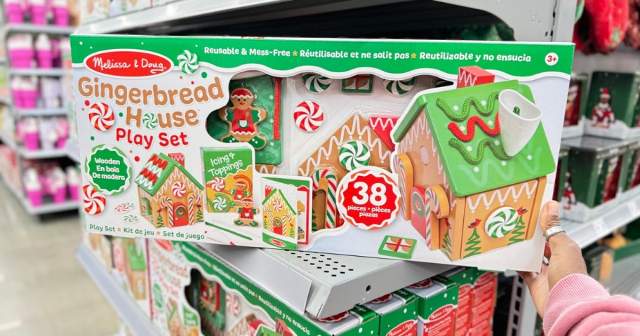 hand touching a Melissa & Doug Gingerbread House Play Set box