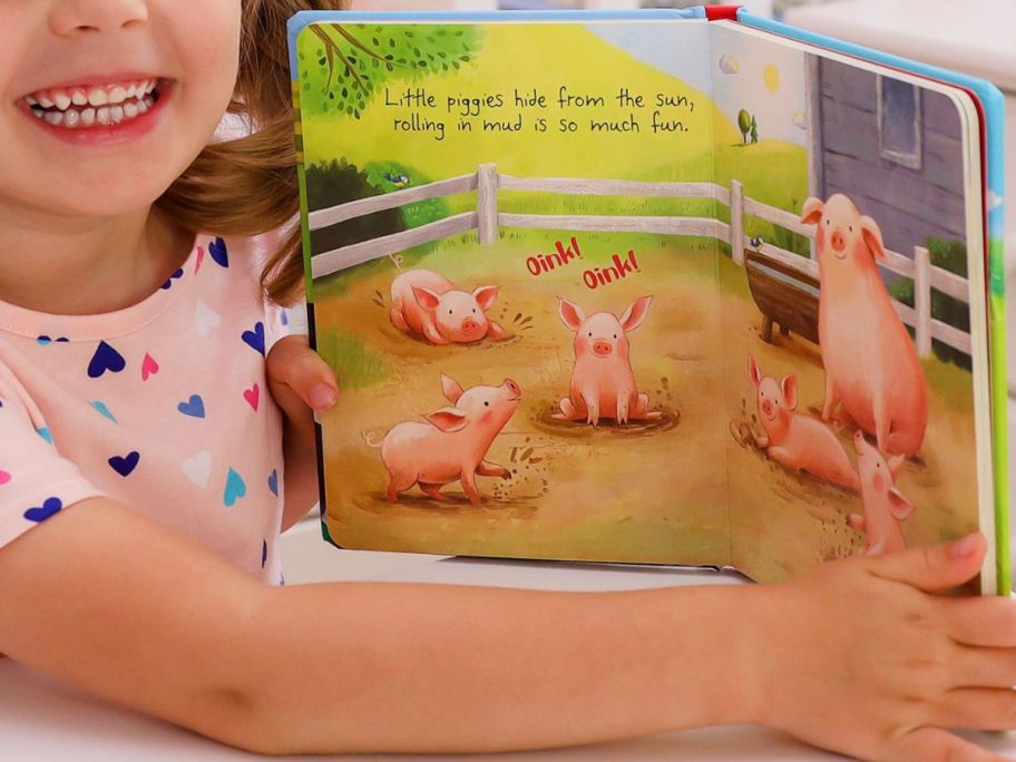 Little girl reading On The Farm Padded Board Book