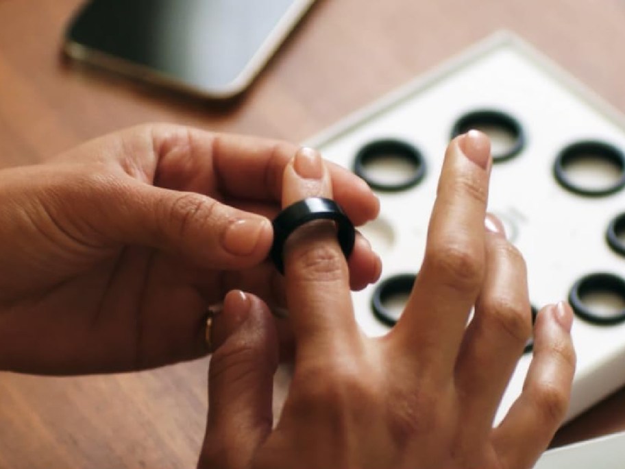 Person trying on oura ring on their finger