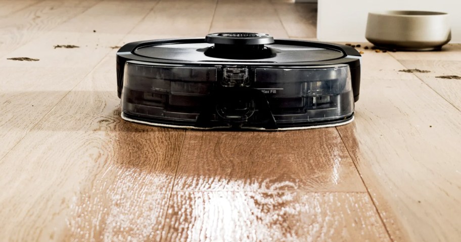 black robot vacuum mopping wood floor