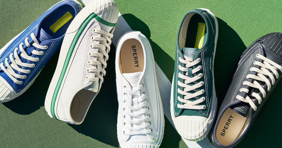 multiple sperry sneakers in a row on a green tennis court