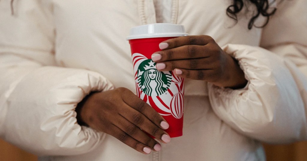 woman in white puffer jacket holding starbucks red cup