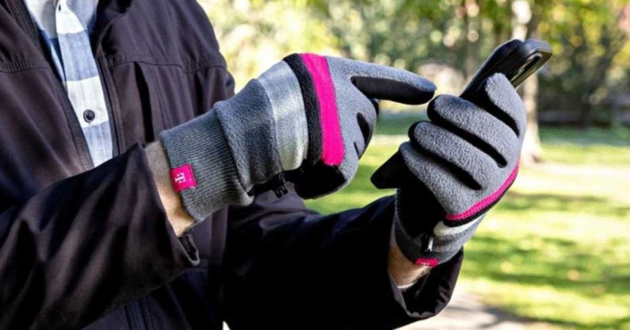 Hands wearing T-Mobile Gloves while using a cell phone