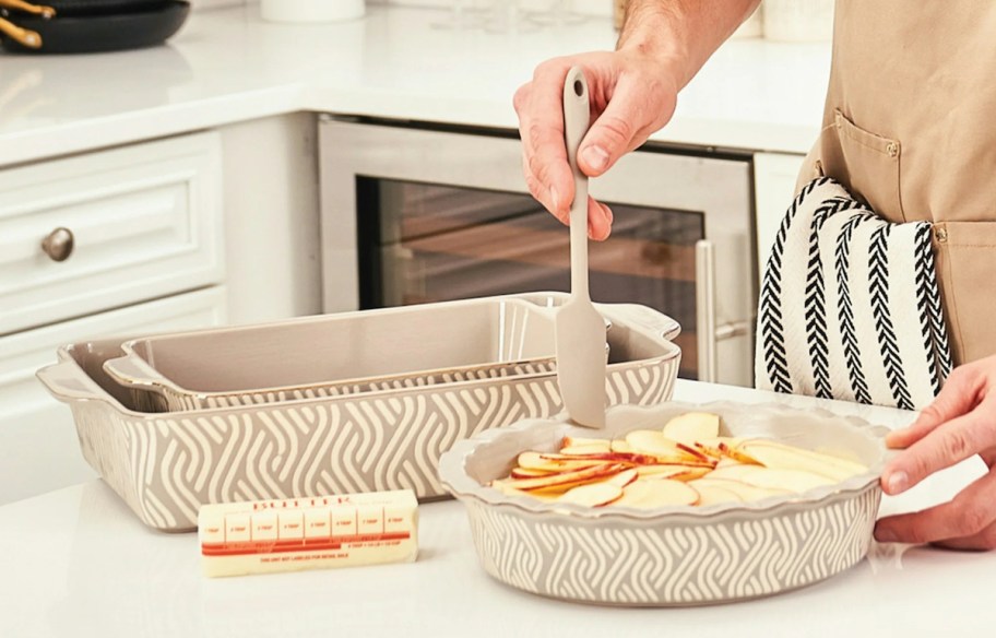 person holding spatula over pie dish on kitchen counter