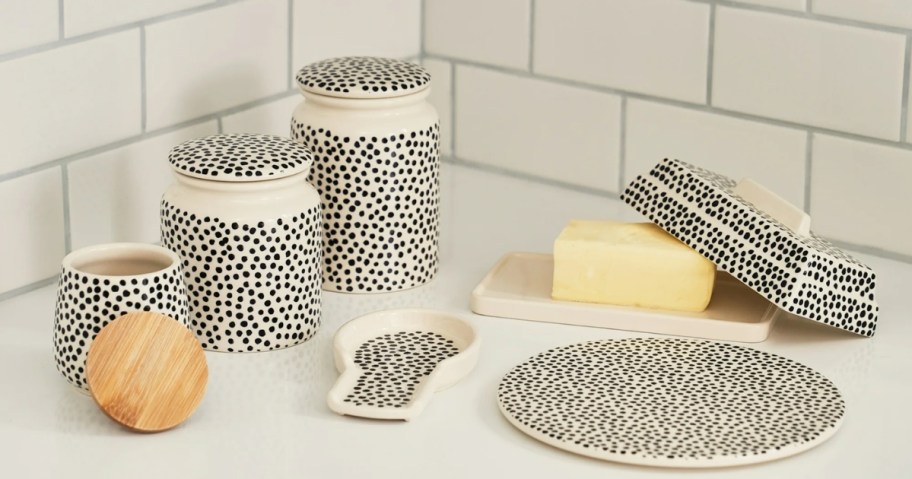 a black and white polka dotted canister set, spoon rest, butter dish with lid and trivet on a kitchen counter