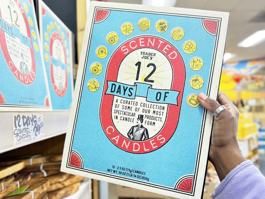 hand grabbing Trader Joe's 12 Days of Scented Candles Advent Calendar from shelf