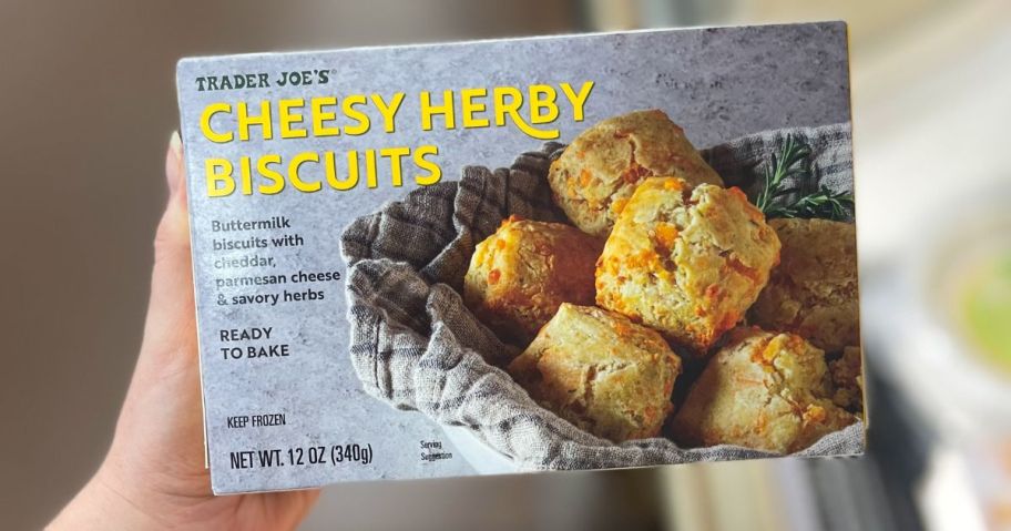 hand holding Trader Joe's Cheesy Herby Biscuits box in store