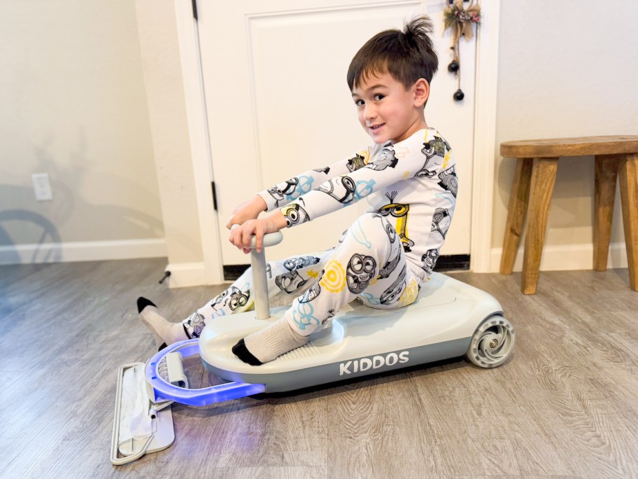 boy sitting on toy with mop and blue light