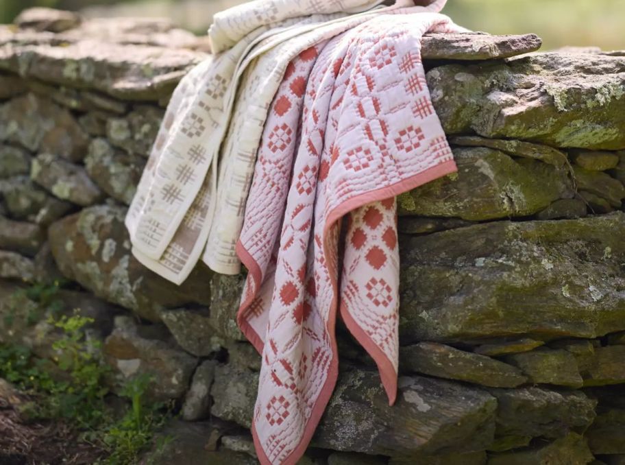 two throw blankets draped over a stone wall