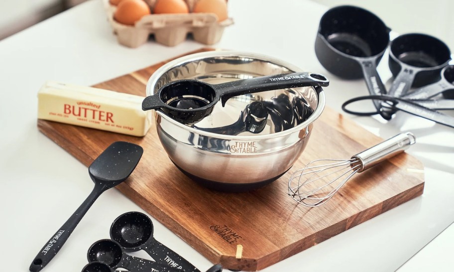 stainless steel bowl with measuring spoons on cutting board