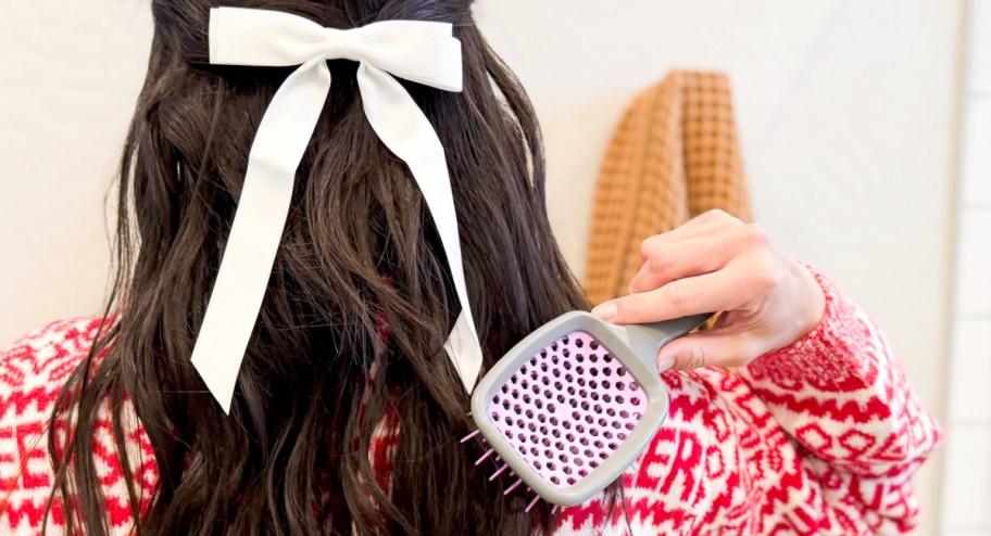 Woman using unbrush on her hair with a bow