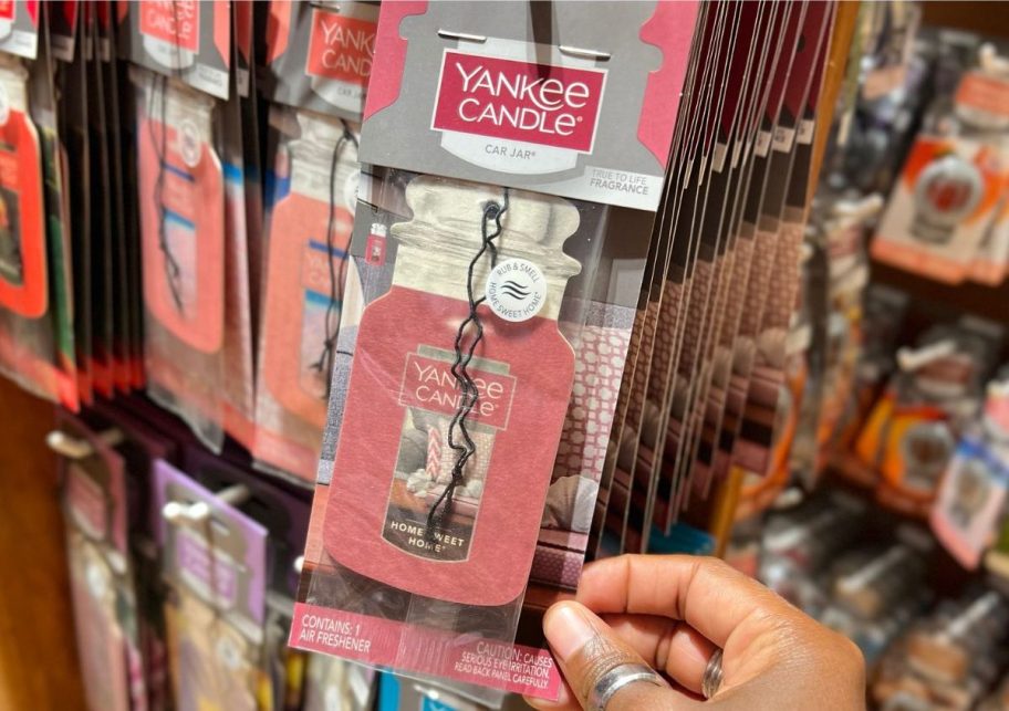 Hand touching a yankee candle air freshener