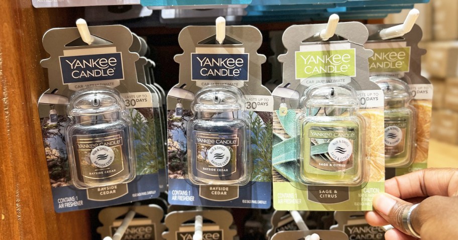 hand touching display of Yankee Candle Car Jar Air Fresheners