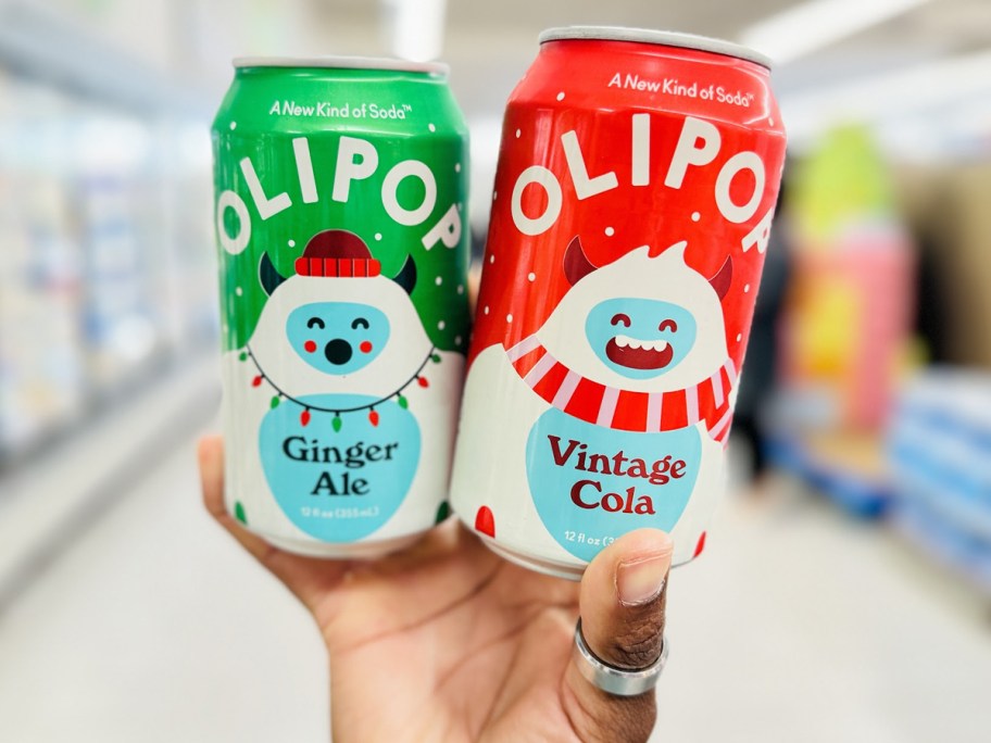 hand holding two cans of olipop 