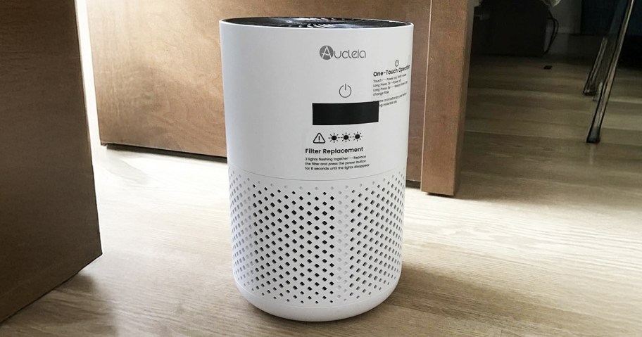 air purifier sitting on a floor by a desk