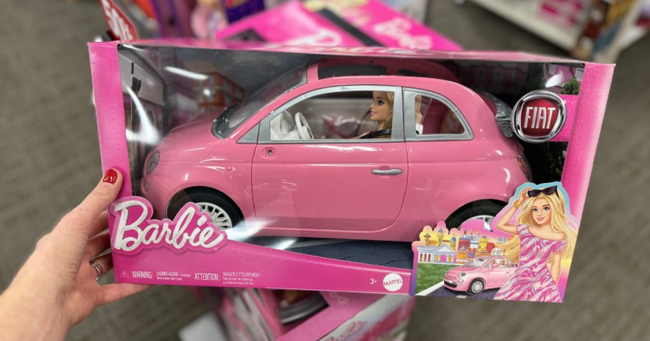 hand holding pink barbie car 