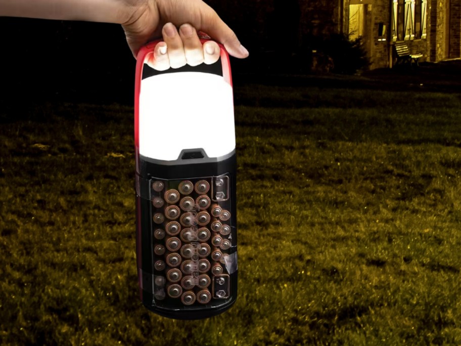 hand holding a lantern with a handle that also is a battery storage case 