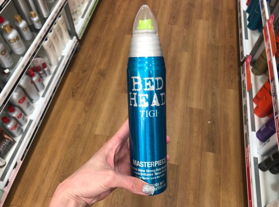 a womans hand holding a can of bed head hair spray