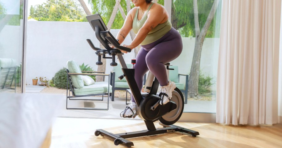 woman riding on black exercise bike 