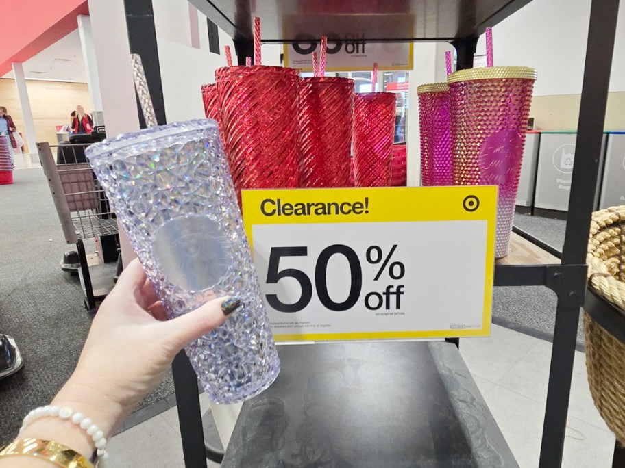 hand holding clear starbucks tumbler near clearance sign 