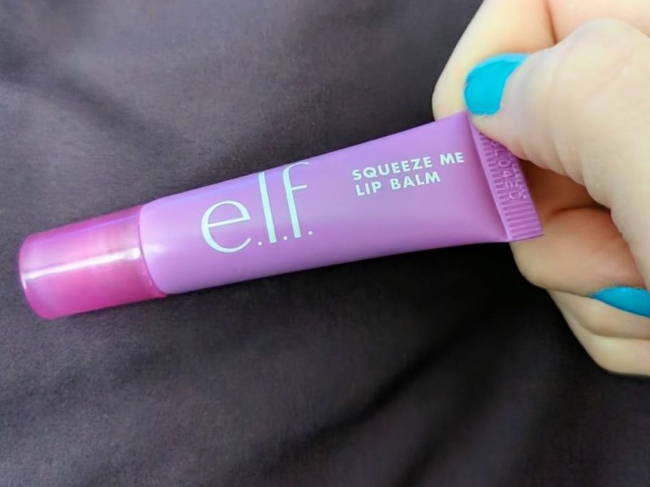 A person holding an e.l.f. Squeeze Me Lip Balm tube